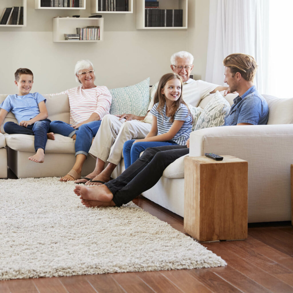 Family sitting on sofa at home | Tri-City Carpet